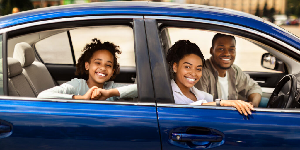 Happy Black Family Sitting In New Blue Car In City